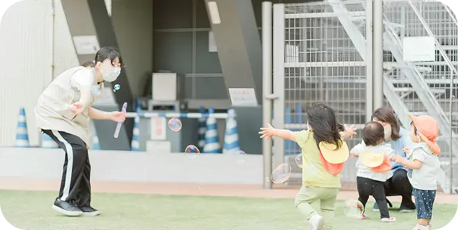 保育士が子どもとシャボン玉遊びをしている様子