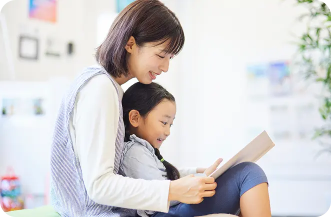 保育士が子どもと絵本を読んでいる様子